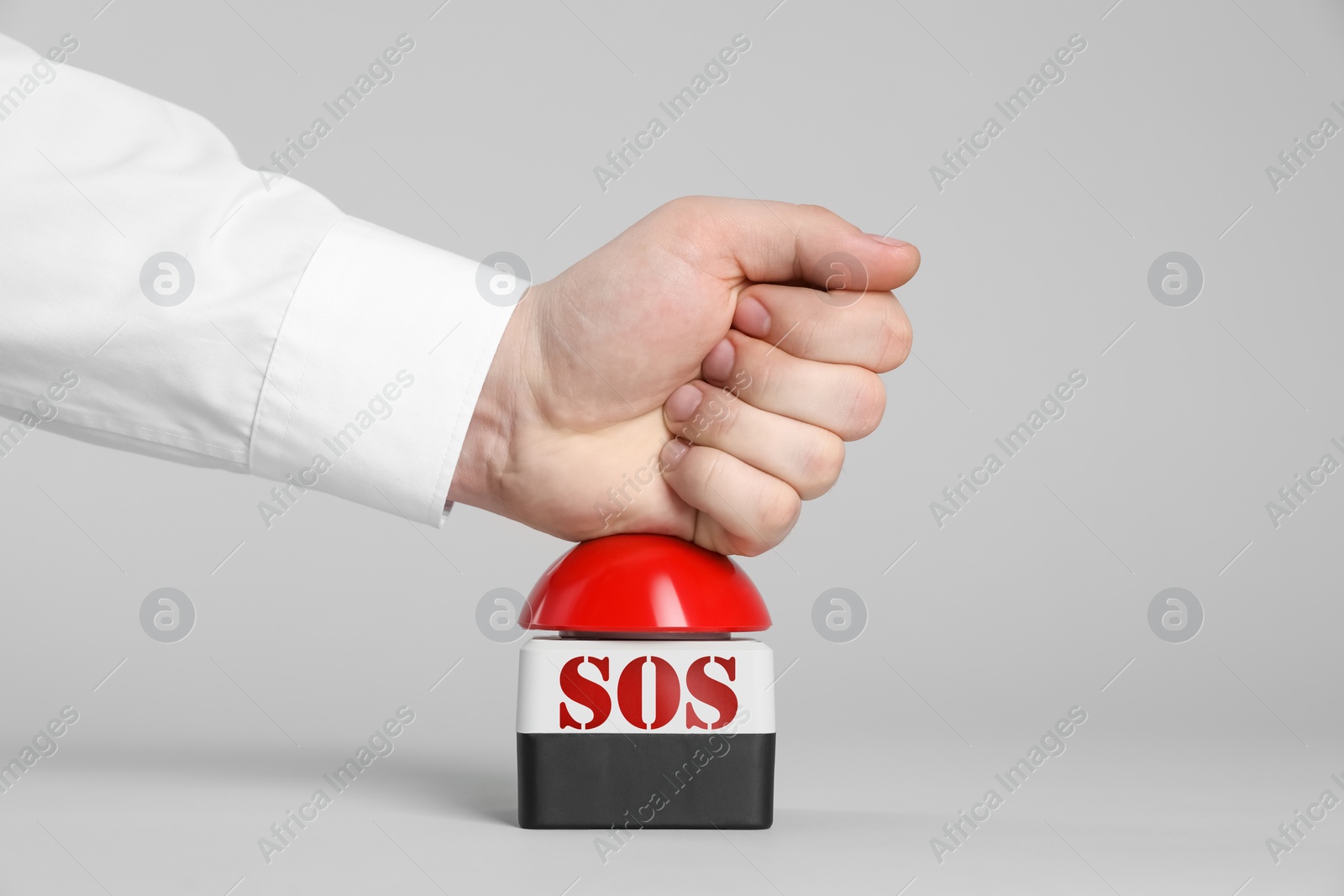 Image of Man pressing red SOS button at white background, closeup