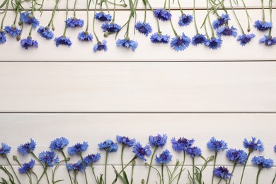 Frame of beautiful blue cornflowers on white wooden background, flat lay. Space for text