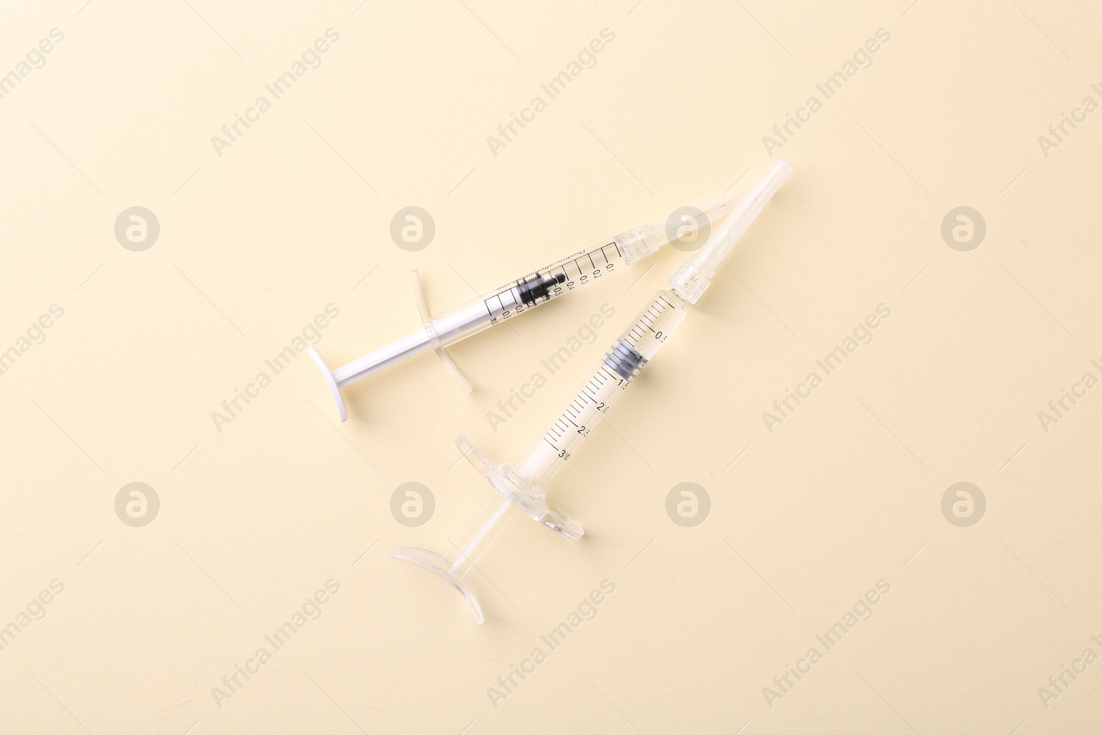 Photo of Injection cosmetology. Two medical syringes on beige background, top view
