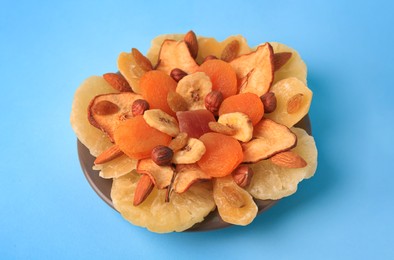 Mixed dried fruits and nuts on light blue background, closeup