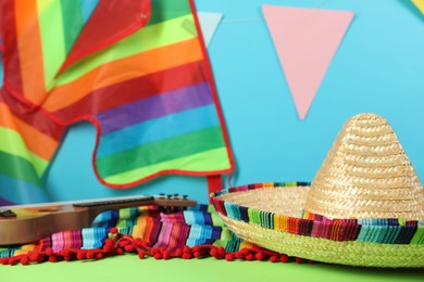 Photo of Mexican sombrero hat and poncho on green table, closeup. Space for text
