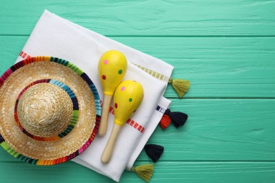 Mexican sombrero hat, maracas and poncho on turquoise wooden table, flat lay. Space for text
