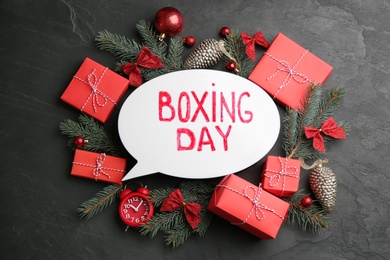 Flat lay composition with Boxing Day sign and Christmas gifts on black table