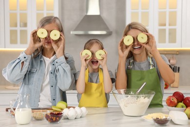 Photo of Three generations. Happy grandmother, her daughter and granddaughter having fun together in kitchen