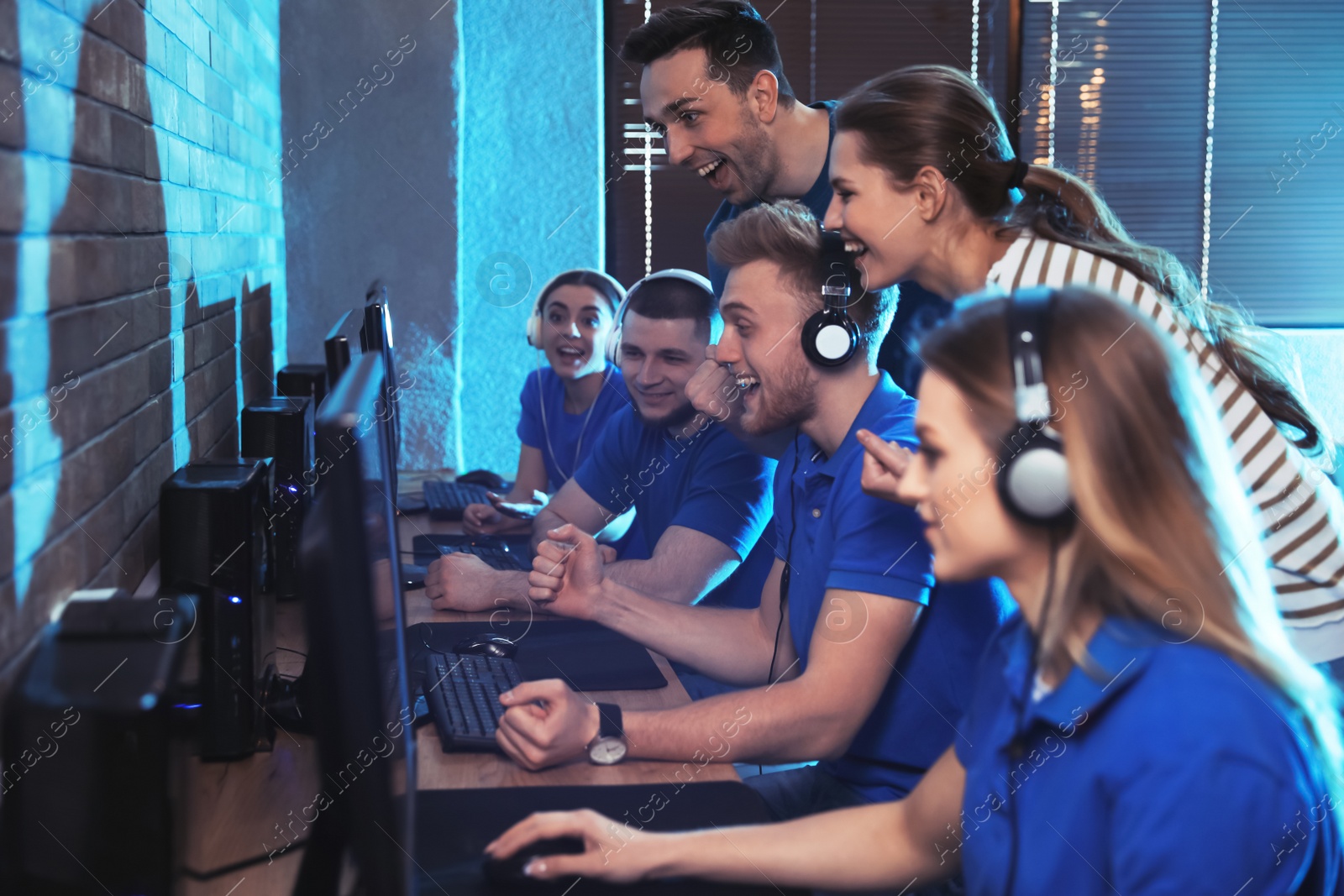 Photo of Group of people playing video games in internet cafe