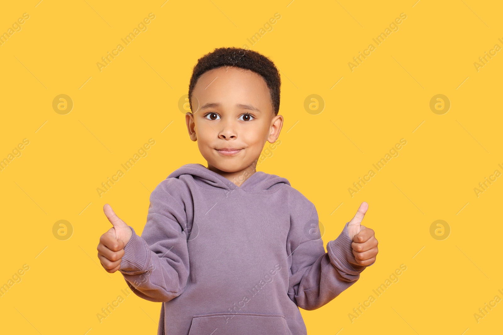 Photo of African-American boy showing thumbs up on yellow background