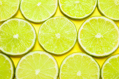 Photo of Juicy fresh lime slices on yellow background, flat lay