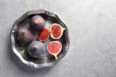 Dish with fresh ripe figs on gray background, top view. Space for text