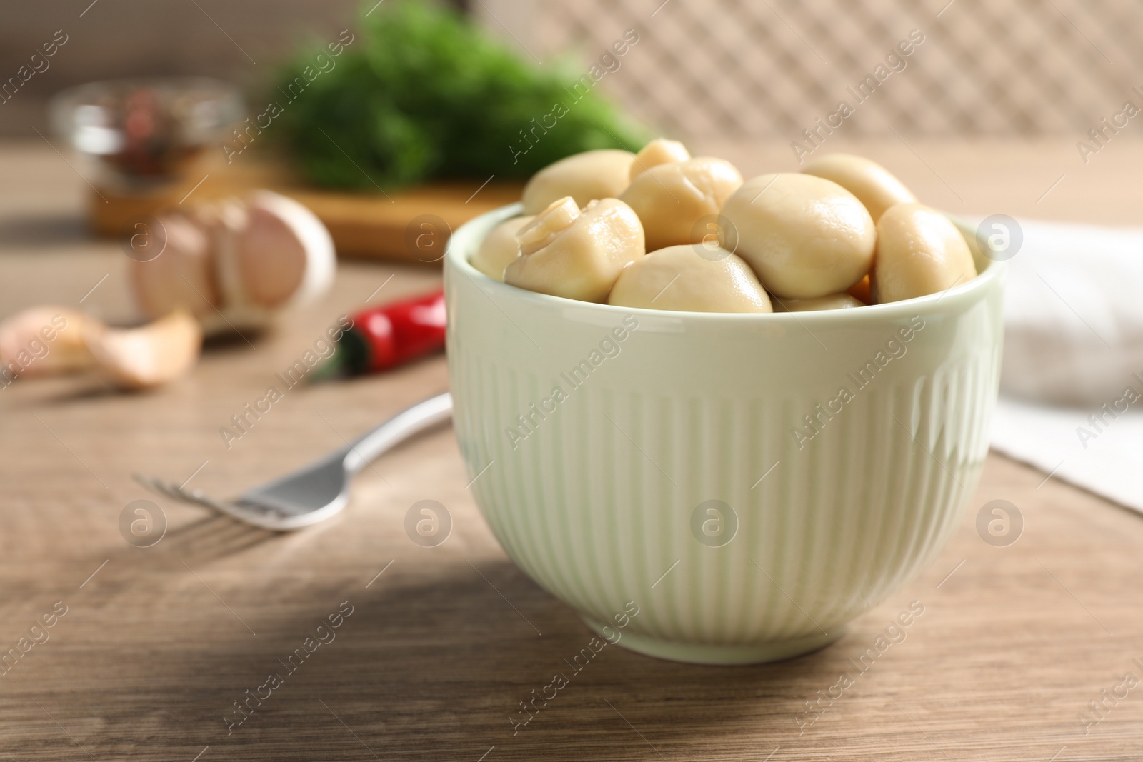 Photo of Delicious marinated mushrooms in bowl on wooden table, closeup