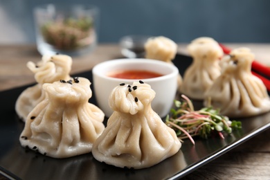 Photo of Plate with tasty baozi dumplings, sprouts and sauce on table, closeup