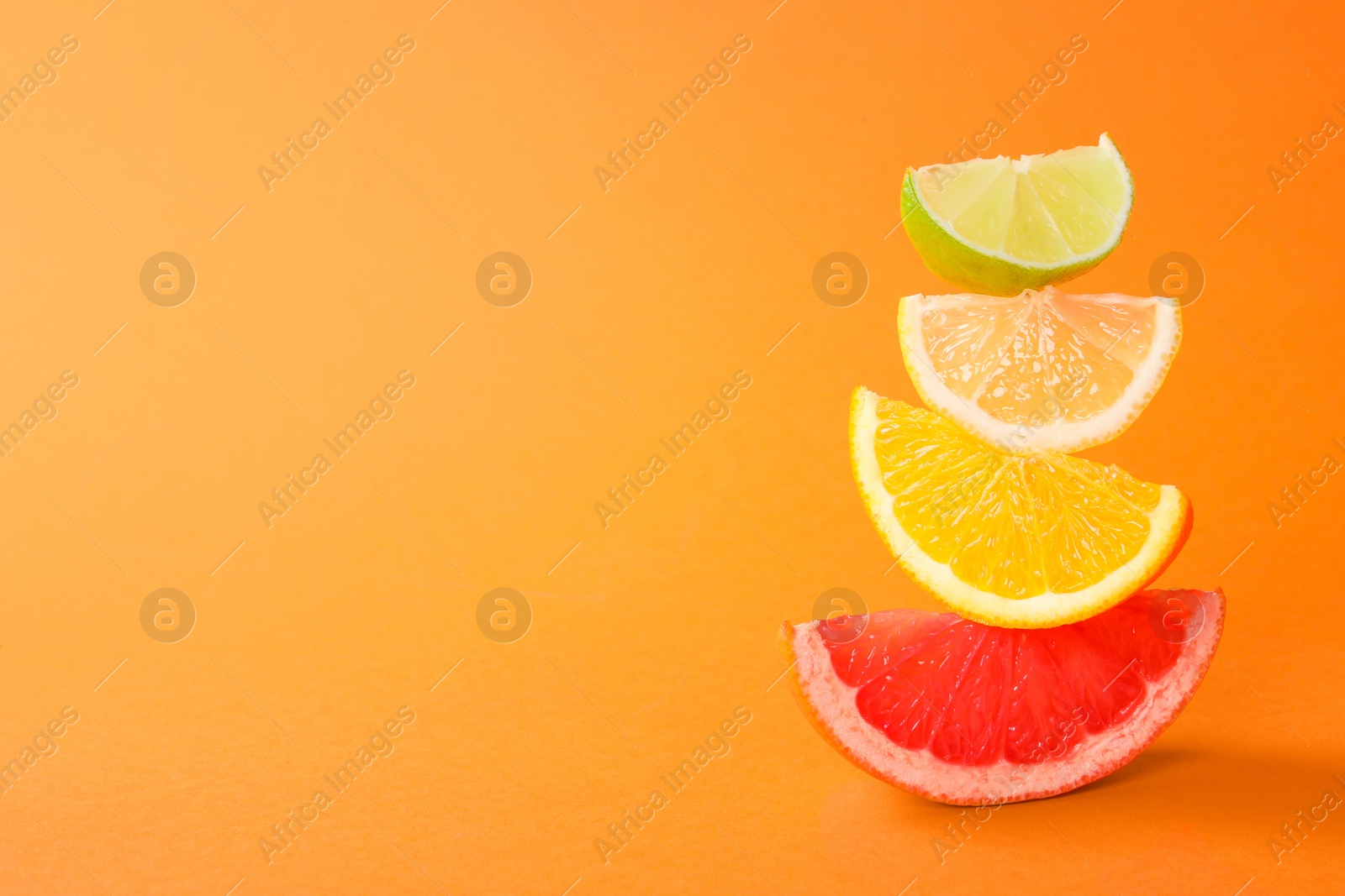 Photo of Cut fresh citrus fruits on orange background, space for text