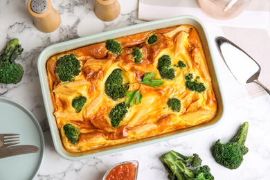 Photo of Tasty broccoli casserole in baking dish on white marble table, flat lay