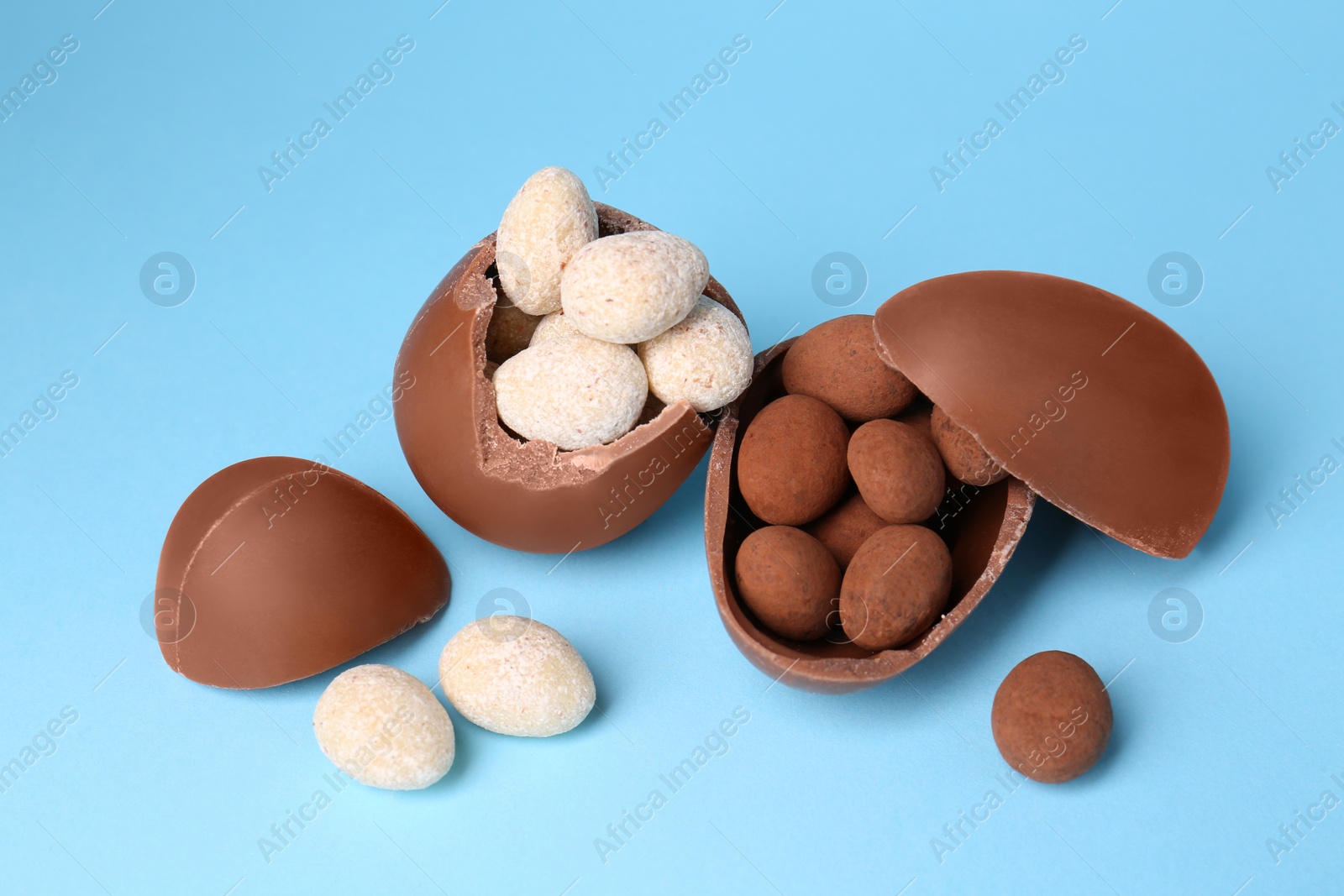 Photo of Tasty broken chocolate eggs and sweets on light blue background