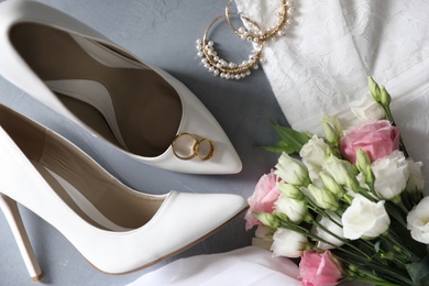 Flat lay composition with wedding dress, white high heel shoes and flowers on grey background