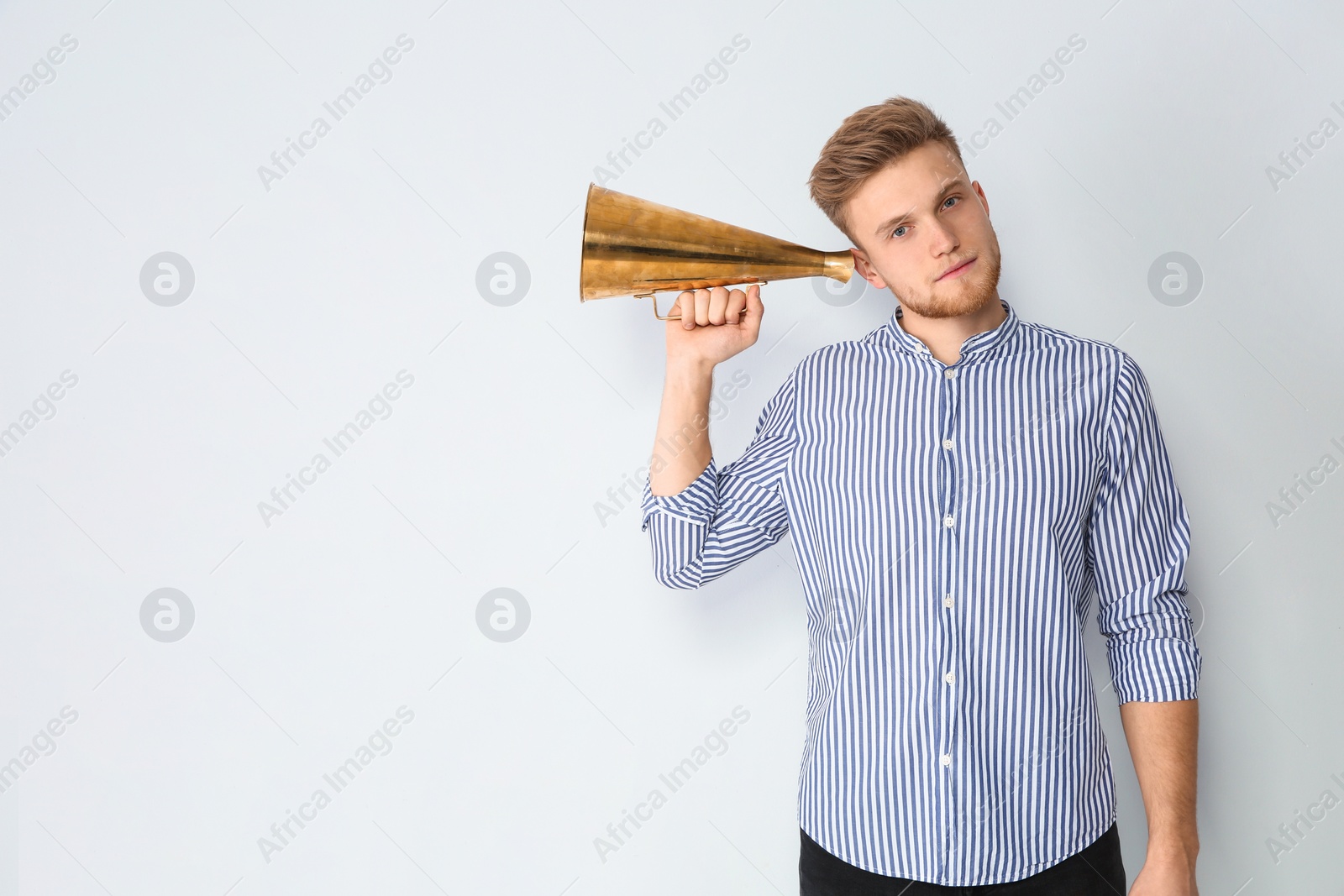 Photo of Young man with megaphone on light background. Space for text