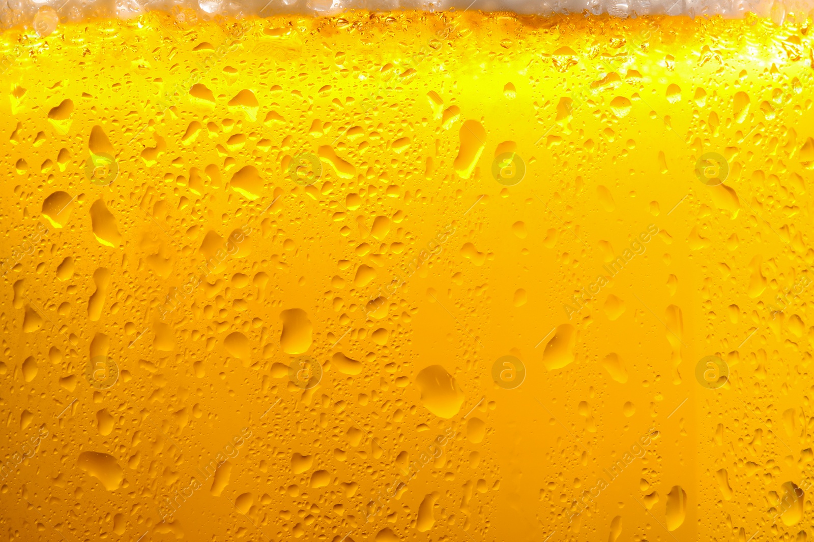 Photo of Glass of tasty cold beer with foam and condensation drops as background, closeup