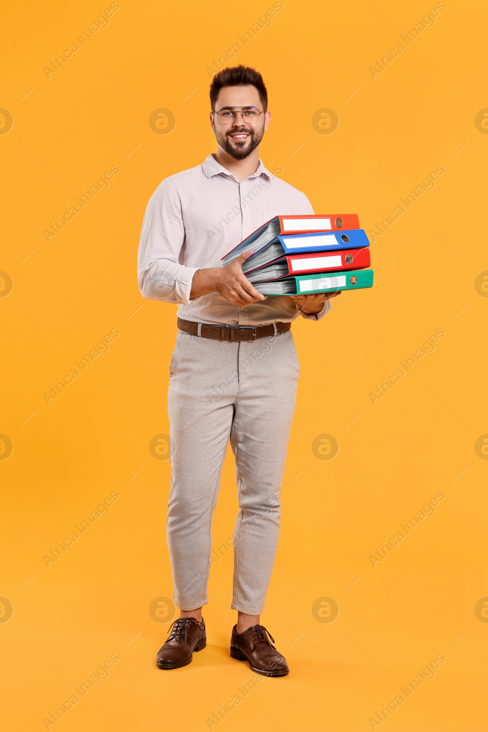 Photo of Happy man with folders on orange background
