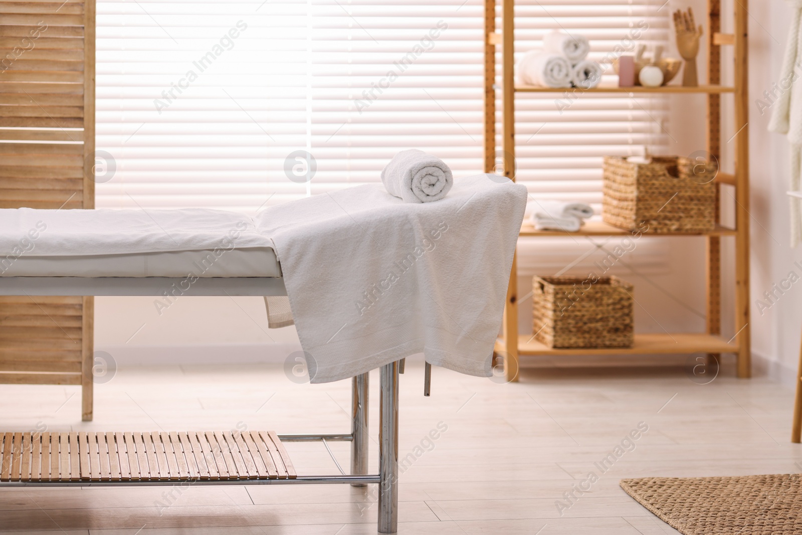 Photo of Comfortable massage table with clean towels in spa center