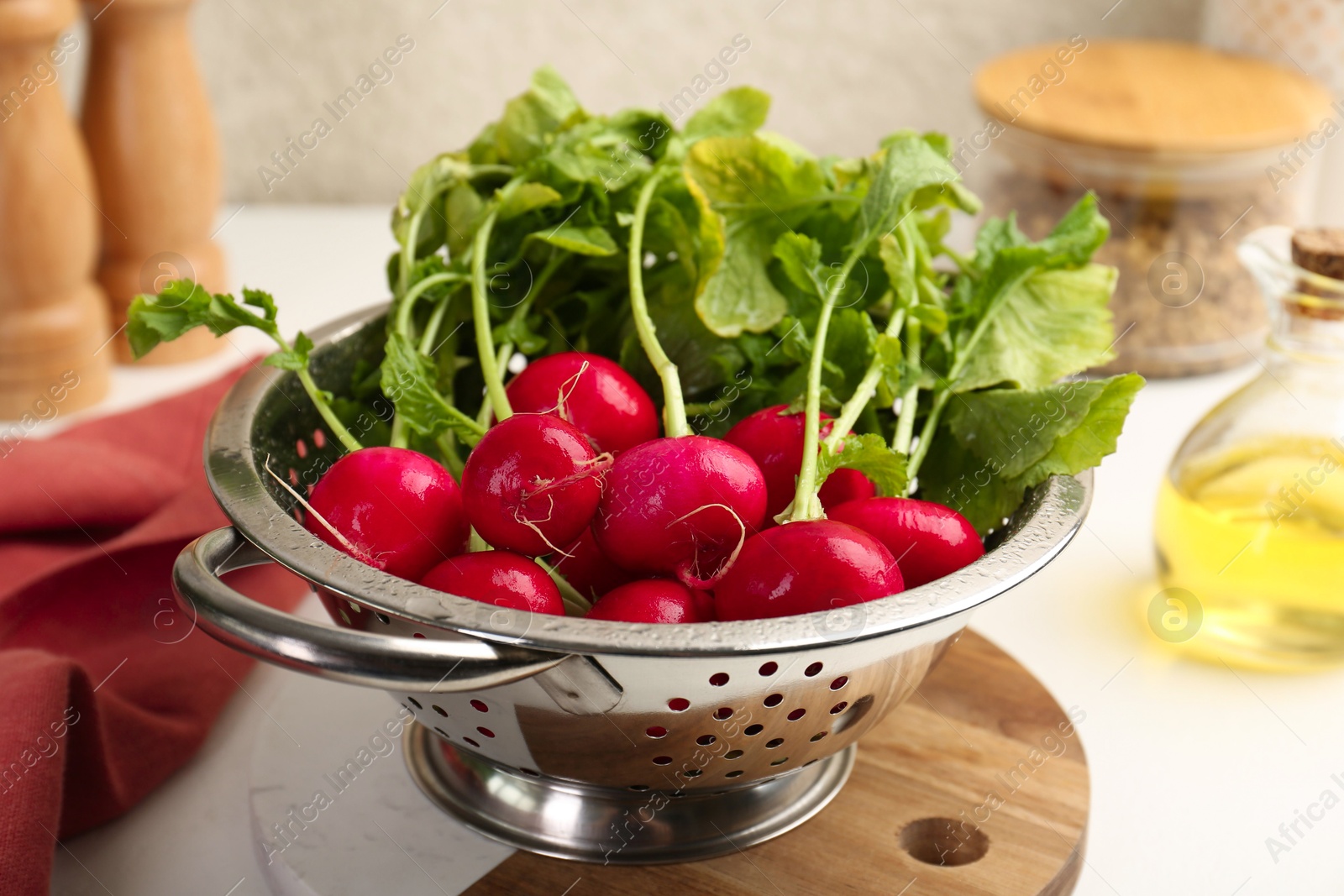 Photo of Wet radish in colander on white table, closeup