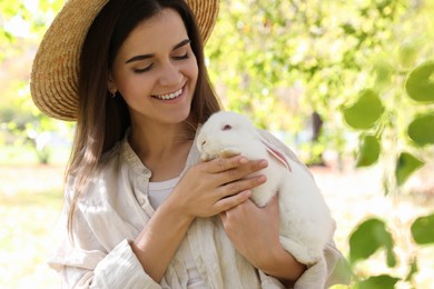 Photo of Happy woman holding cute white rabbit in park