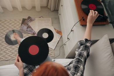 Photo of Young woman listening to music with turntable in bedroom, above view