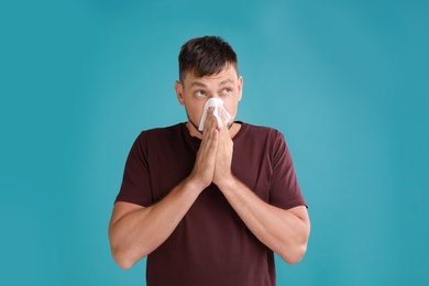 Photo of Man suffering from allergy on blue background
