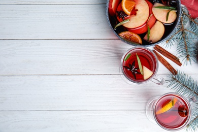 Photo of Tasty mulled wine with spices on white wooden table, flat lay. Space for text