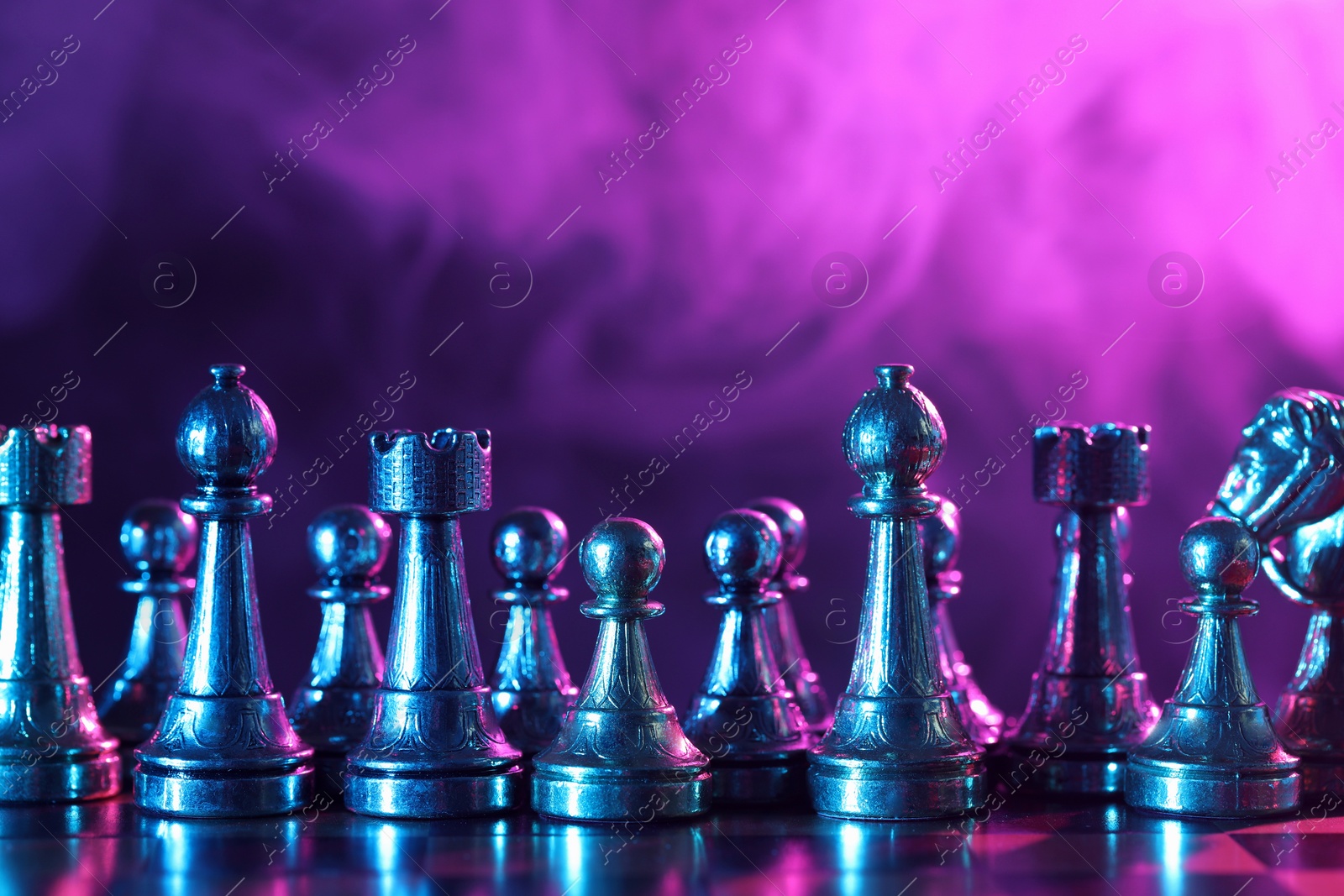 Photo of Chess pieces on checkerboard in color light. Space for text