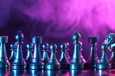 Photo of Chess pieces on checkerboard in color light. Space for text