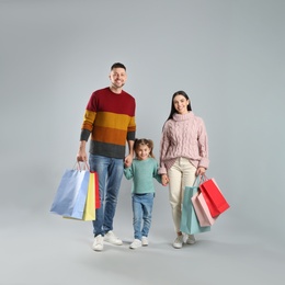 Photo of Happy family with paper bags on grey background. Christmas shopping