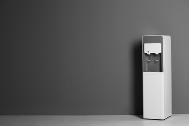 Photo of Modern water cooler against gray wall with space for text