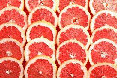 Many sliced fresh grapefruits as background, top view