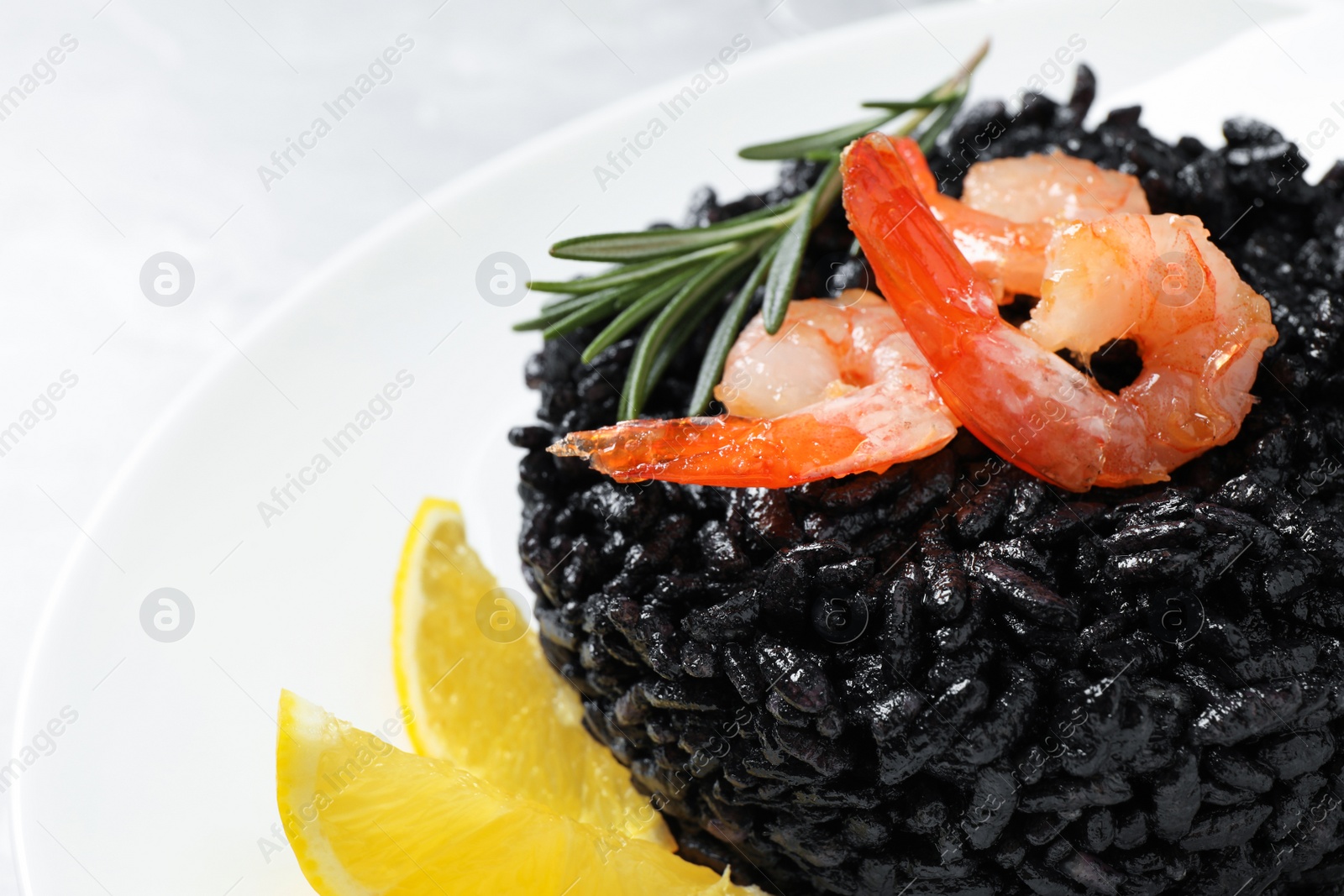 Photo of Delicious black risotto with shrimps and lemon in plate, closeup