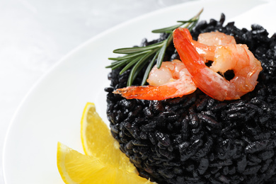Photo of Delicious black risotto with shrimps and lemon in plate, closeup