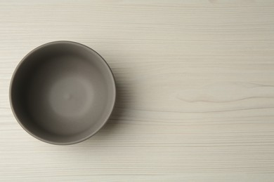 Photo of Stylish empty ceramic bowl on white wooden table, top view and space for text. Cooking utensil