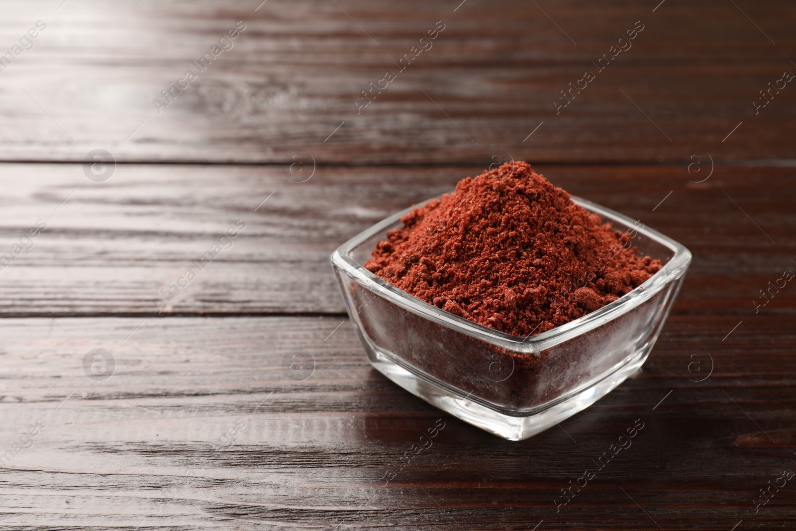 Photo of Dried cranberry powder in glass bowl on wooden table. Space for text