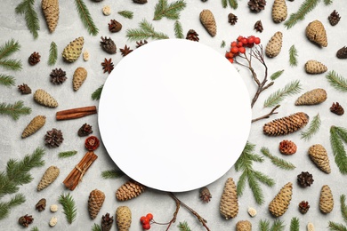 Flat lay composition with pinecones and blank card on light grey background, space for text