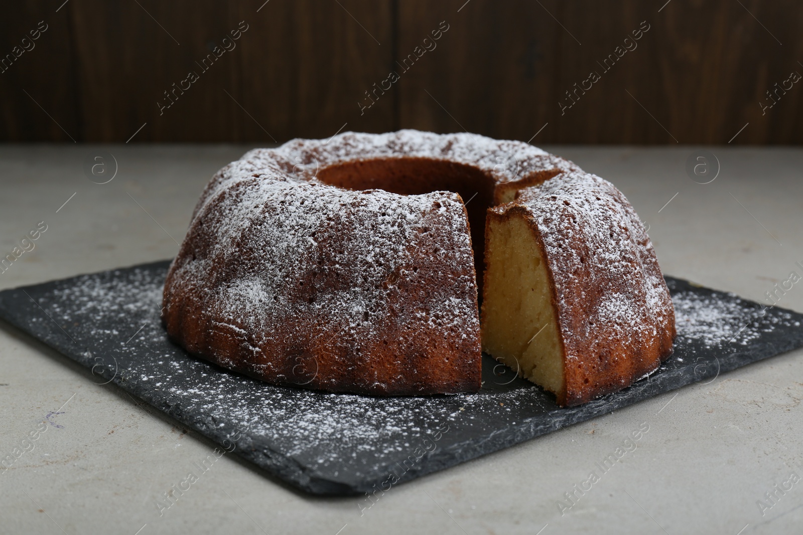 Photo of Homemade yogurt cake with powdered sugar on light grey table