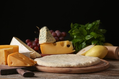 Photo of Pizza crust and fresh ingredients on wooden table