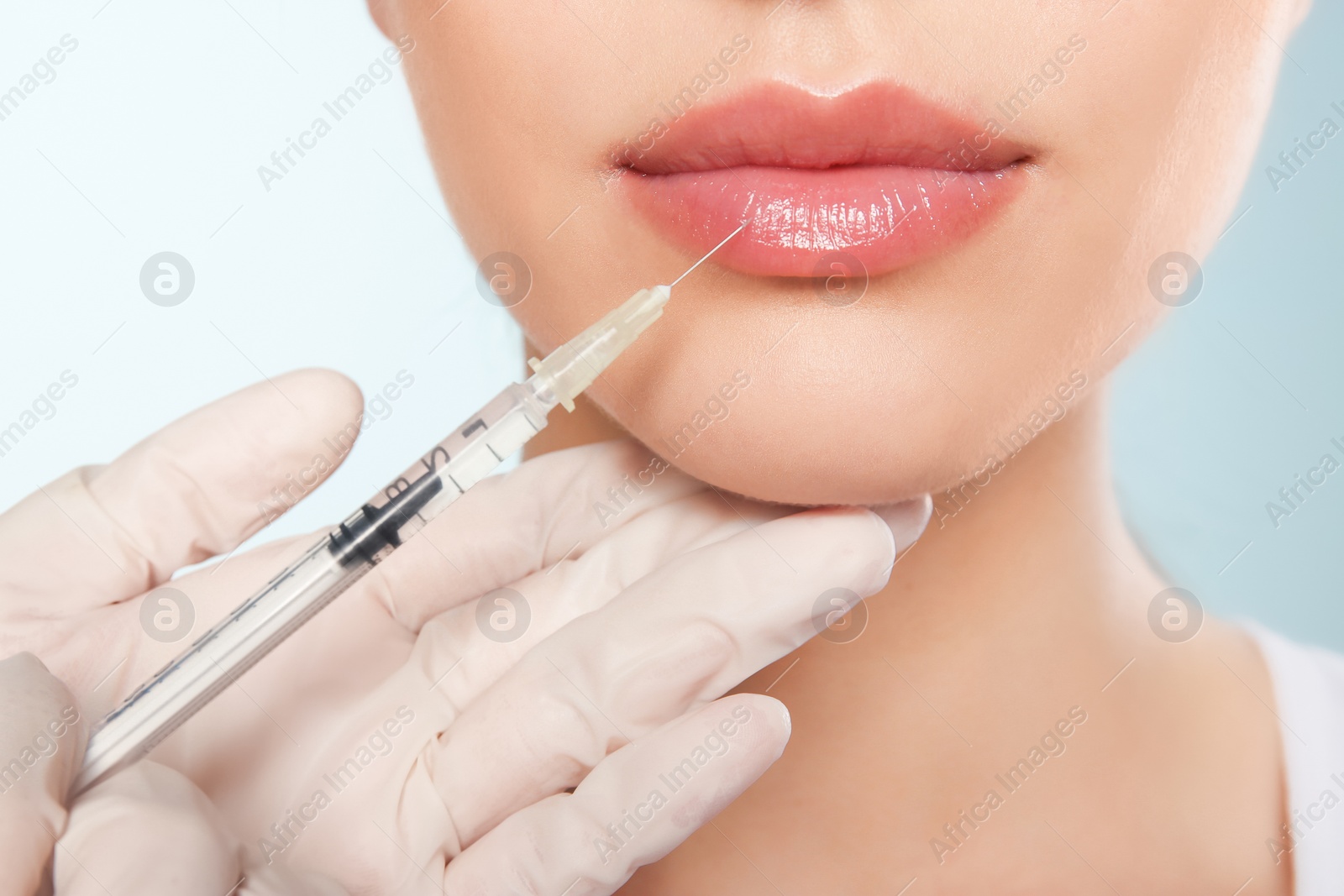 Photo of Young woman getting lip injection on color background, closeup