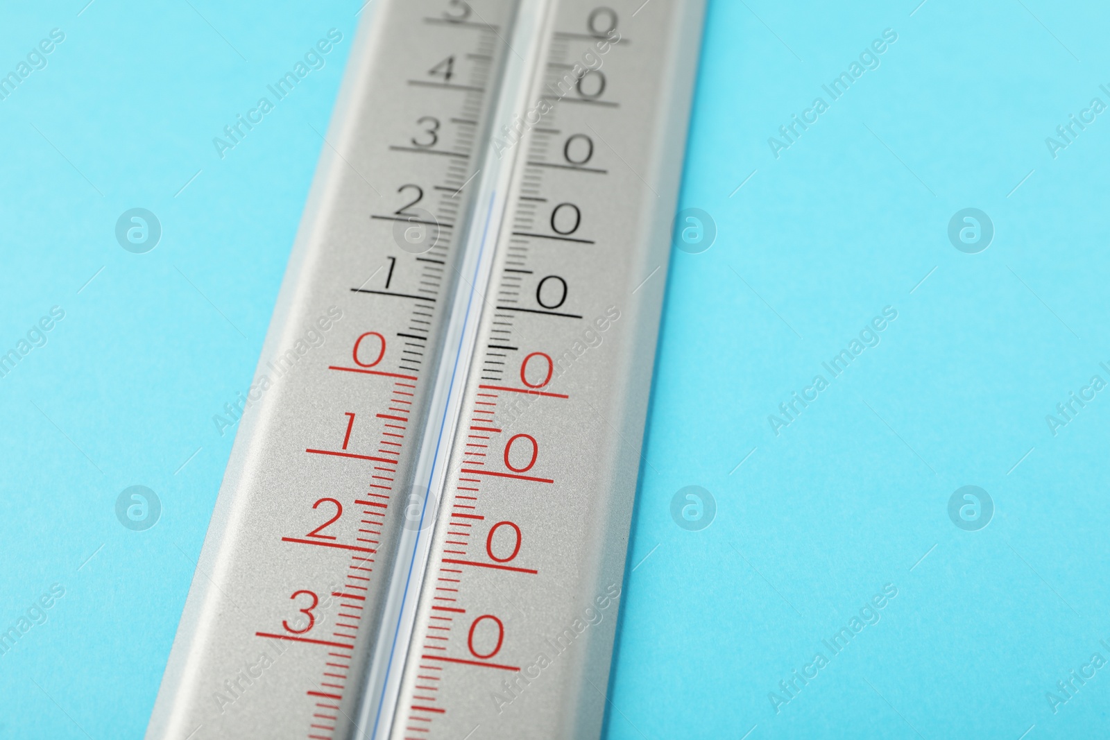 Photo of Weather thermometer on light blue background, closeup. Space for text