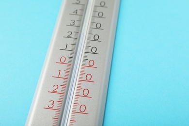 Photo of Weather thermometer on light blue background, closeup. Space for text