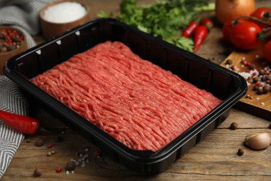 Photo of Minced meat in plastic container and other ingredients on wooden table
