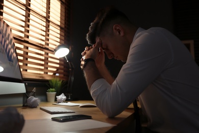 Photo of Businessman stressing out at workplace late in evening
