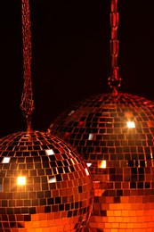 Photo of Shiny bright disco balls under red light, closeup