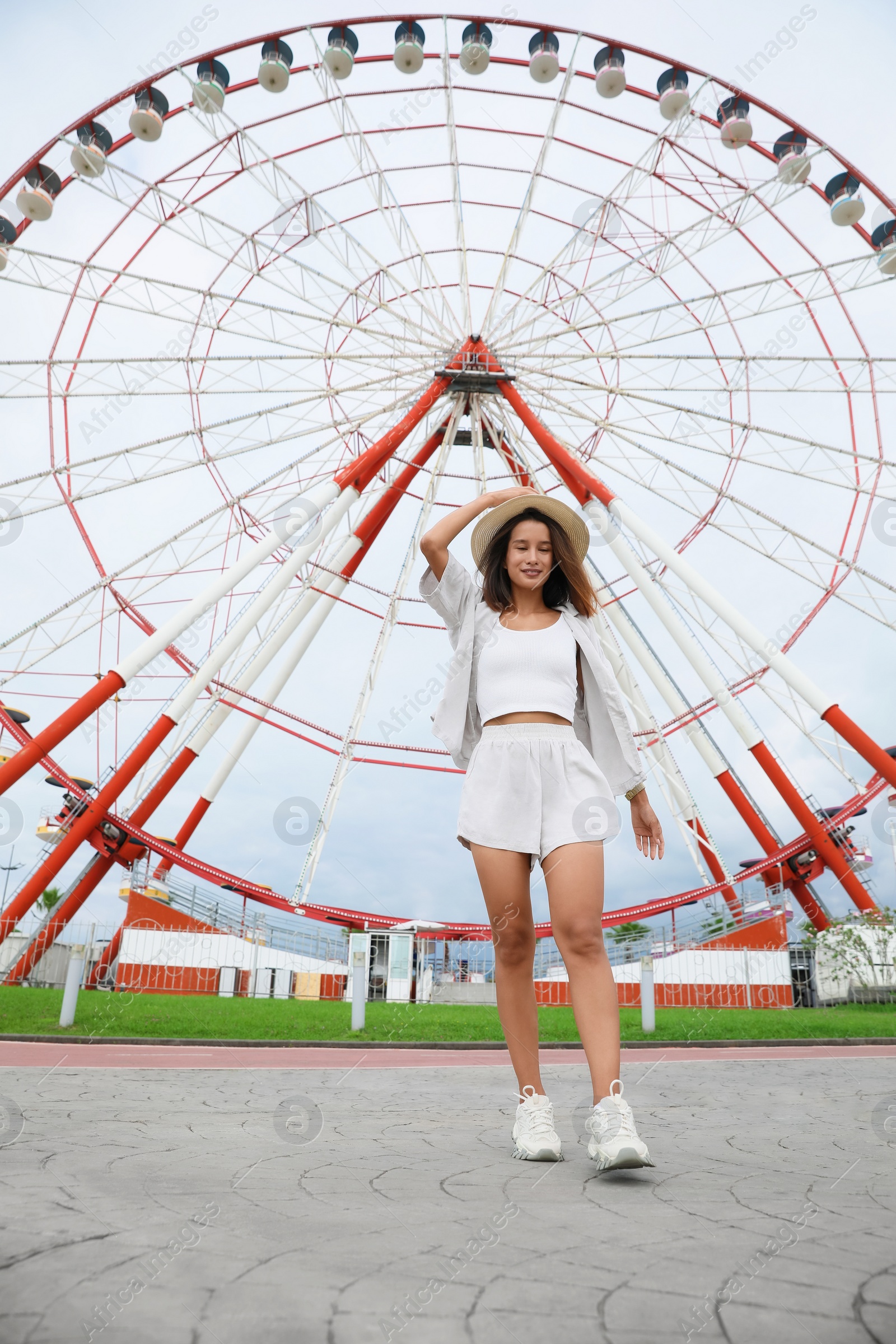 Photo of Beautiful young woman near Ferris wheel outdoors, low angle view