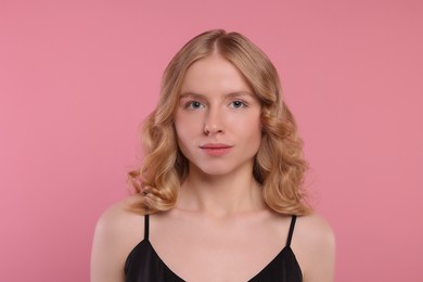 Portrait of beautiful woman with blonde hair on pink background