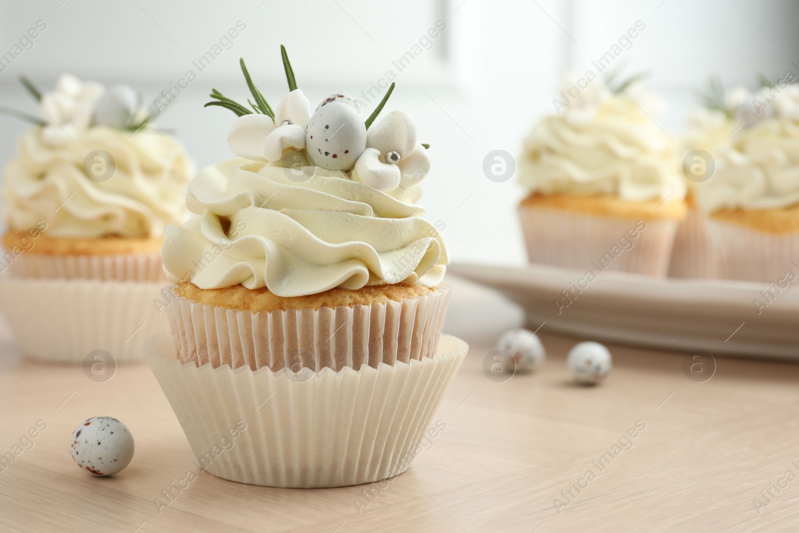 Photo of Tasty Easter cupcakes with vanilla cream on wooden table, closeup