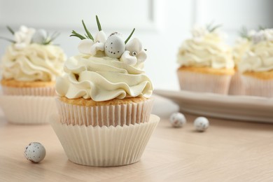 Photo of Tasty Easter cupcakes with vanilla cream on wooden table, closeup