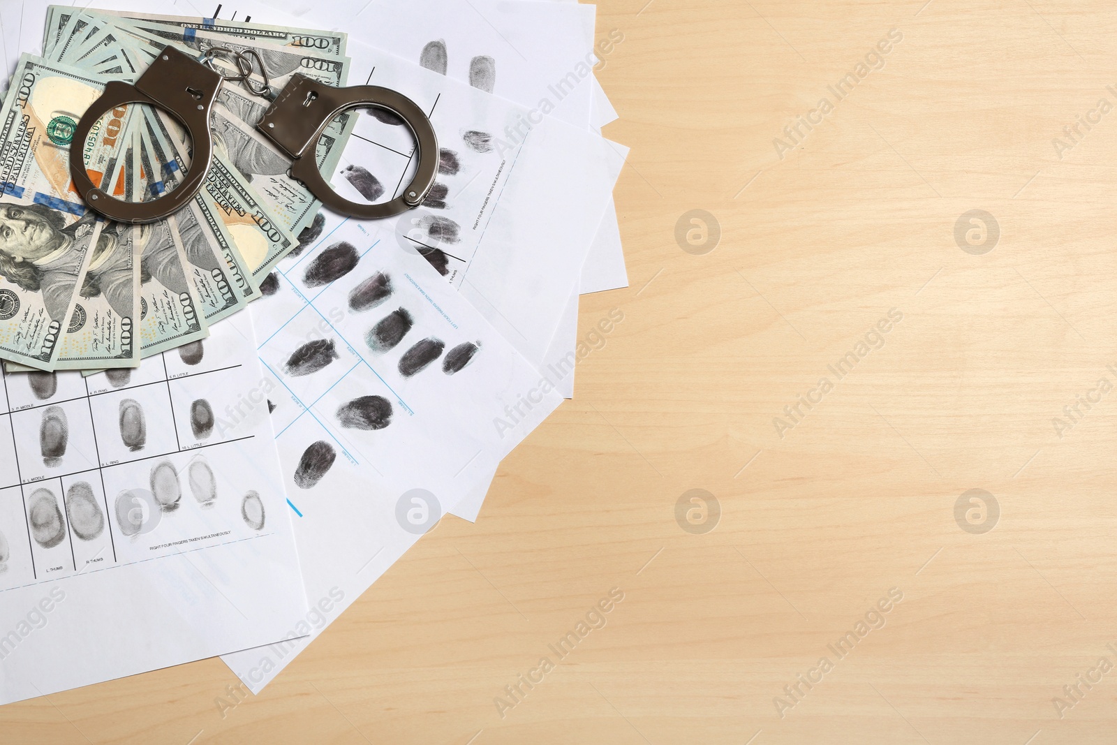 Photo of Flat lay composition with fingerprints, cash and handcuffs on wooden background, space for text